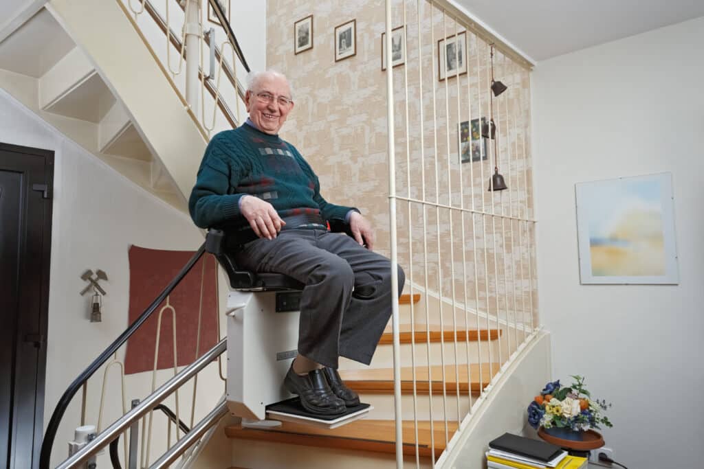 Elderly man uses stair lift in his home