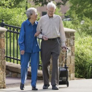 elderly man holds onto Oxlife Independence Portable Oxygen Concentrator while walking with wife