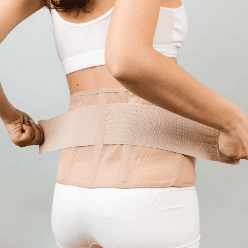 Person wearing a beige abdominal binder around the torso for support and recovery.