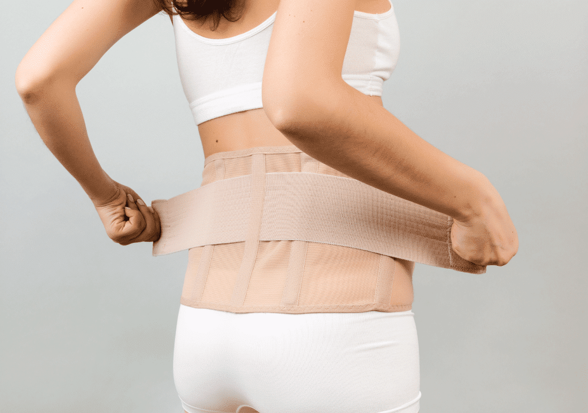 Person wearing a beige abdominal binder around the torso for support and recovery.