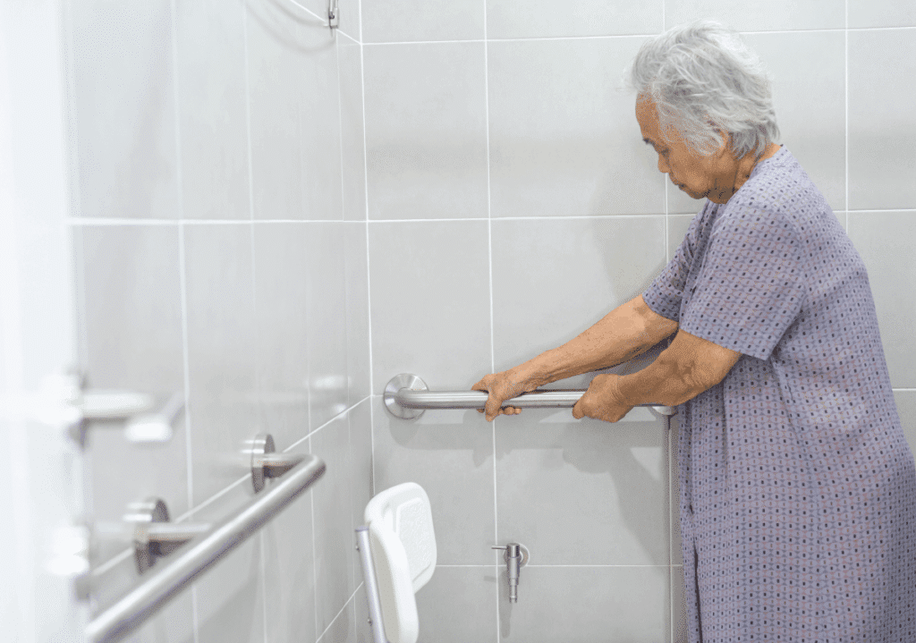 Senior woman using grab bars in bathroom for safe recovery after surgery at home