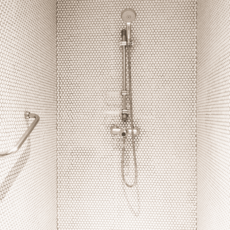 Accessible shower with grab bar and handheld showerhead for safe bathing in small bathrooms