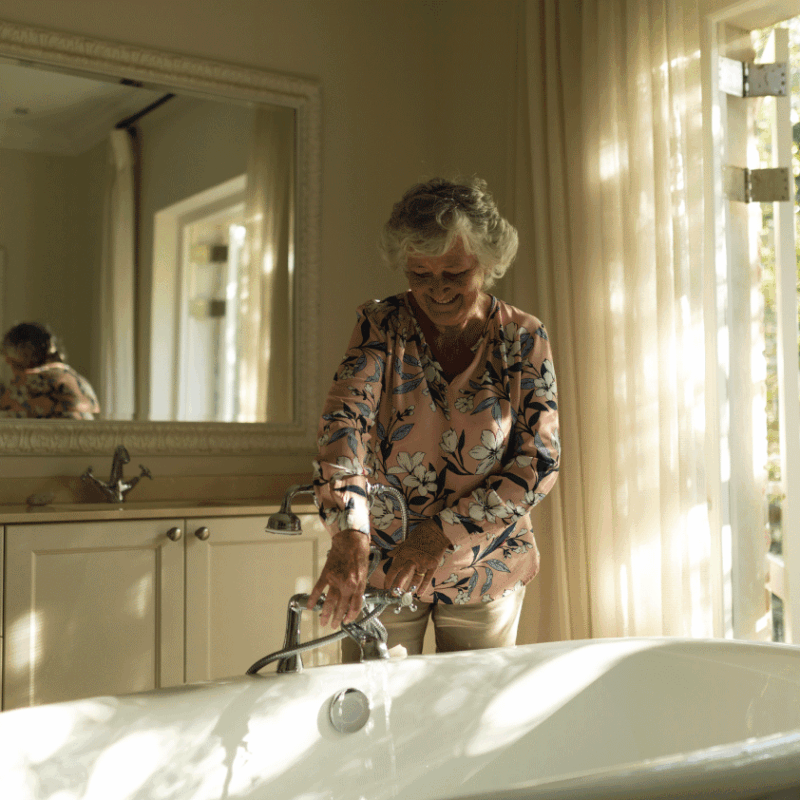 Smiling senior woman preparing bath safely in a sunlit bathroom
